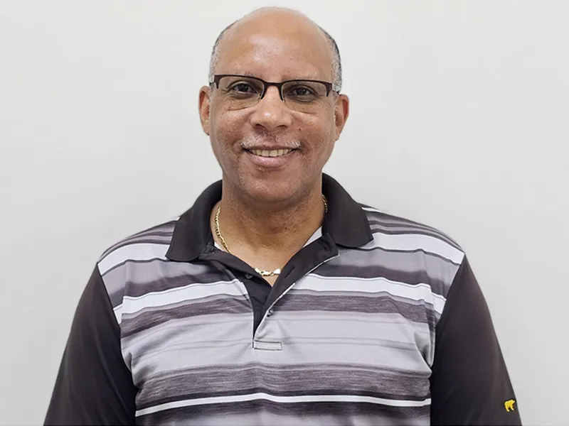 A closeup of a man, he smiles at the camera, he has on glasses and a collared shirt