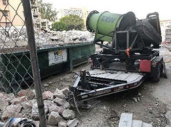 A construction site, you see rocks and a large green garbage bin