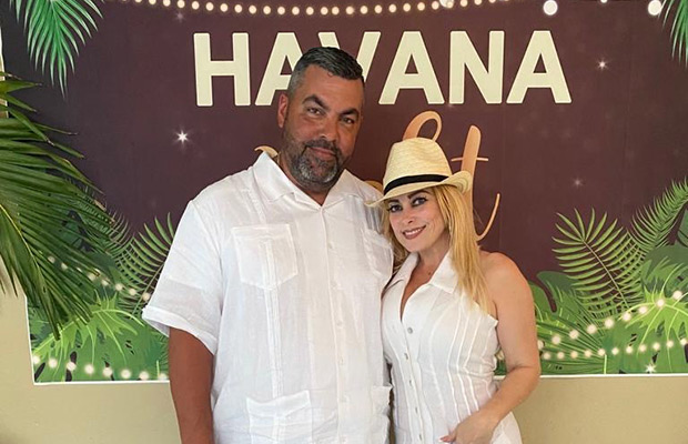 A man and woman wearing all white, they look towards the camera, behind them it reads Havana