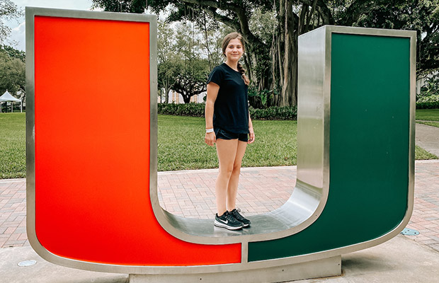 A young woman standing on a large U sign