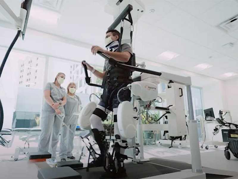 A man on a Zero G Gait Trainers, there are two medical professionals next to him watching him use the machine