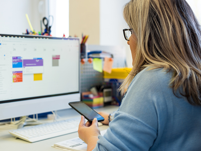 A woman in an office during a phone call, using an online calendar