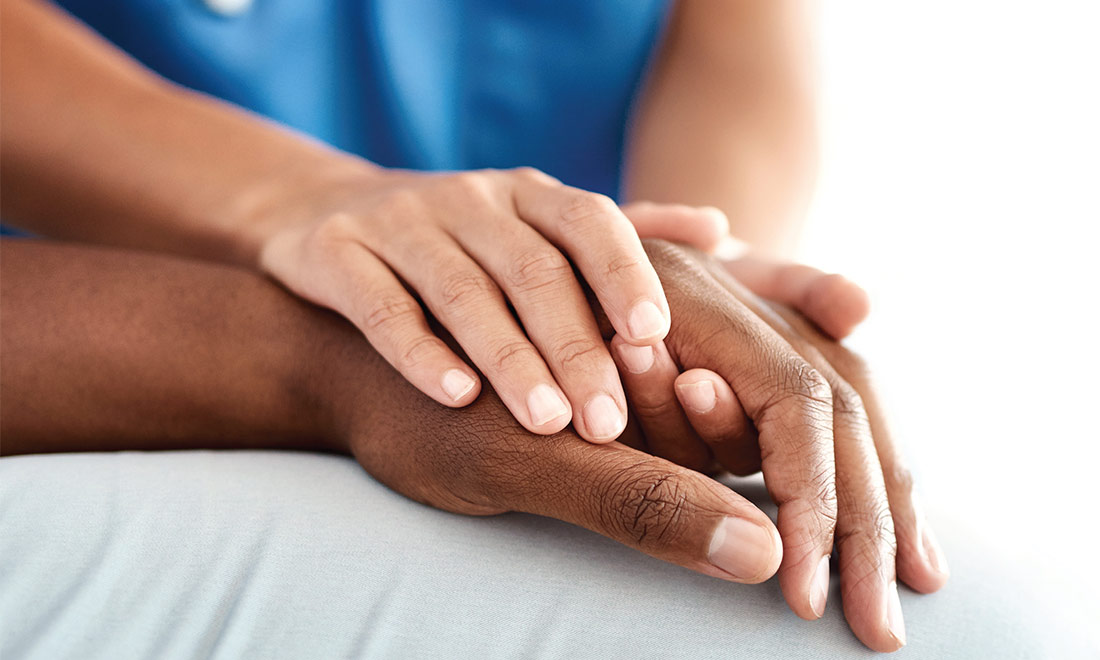 Closeup of a physicians hands holding a patients hand