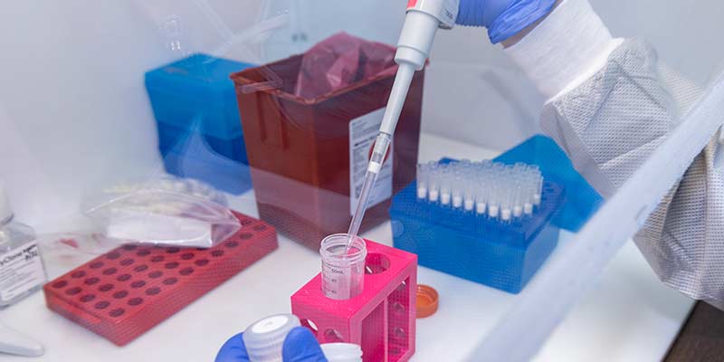 Closeup of a person running lab tests by putting liquids into a test tube