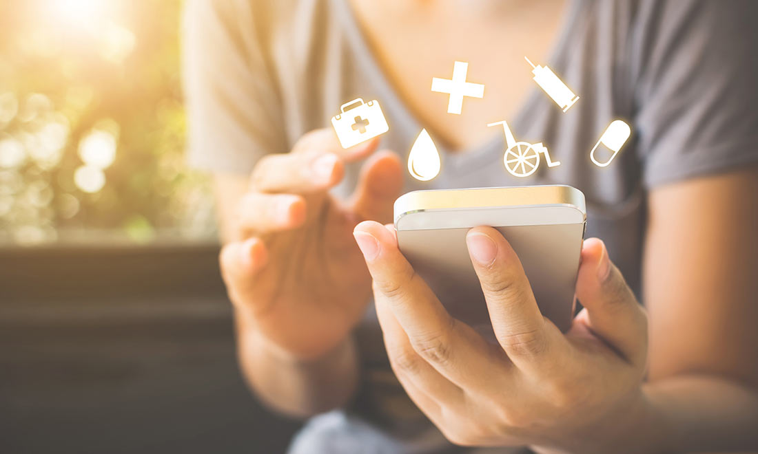 Closeup of a woman using a mobile phone, medical icons are above the phone