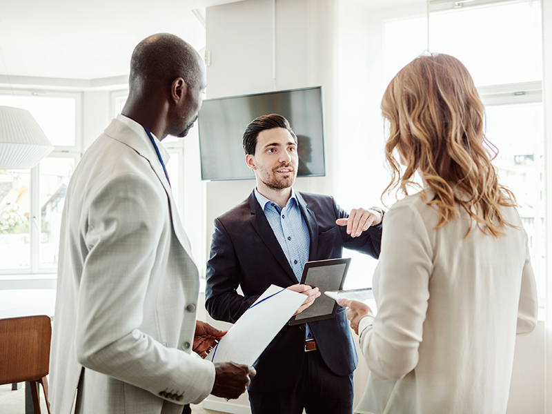 Three business people standing and speaking to each other