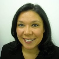 A headshot of a woman, she smiles at the camera, she has dark hair and a dark shirt on
