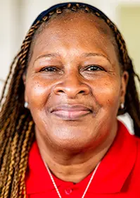 A closeup of a women, she smiles at the camera, she has on a red top