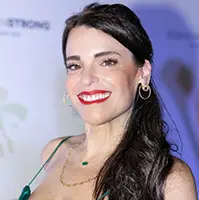 A closeup of a women, she smiles at the camera, she has long dark hair