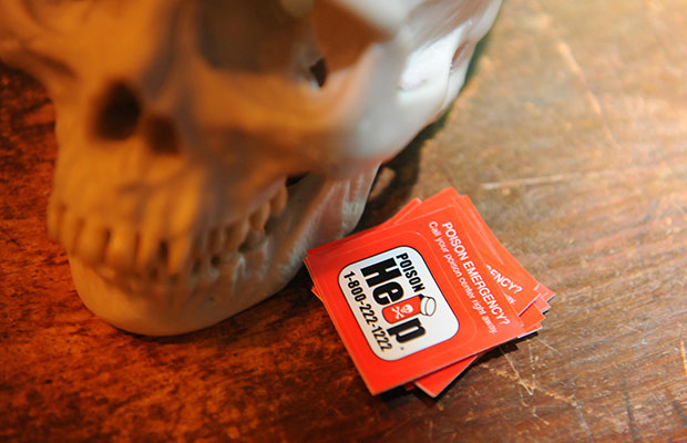 A skull, next to it is a card that reads poison emergency? poison help 1-800-222-1222
