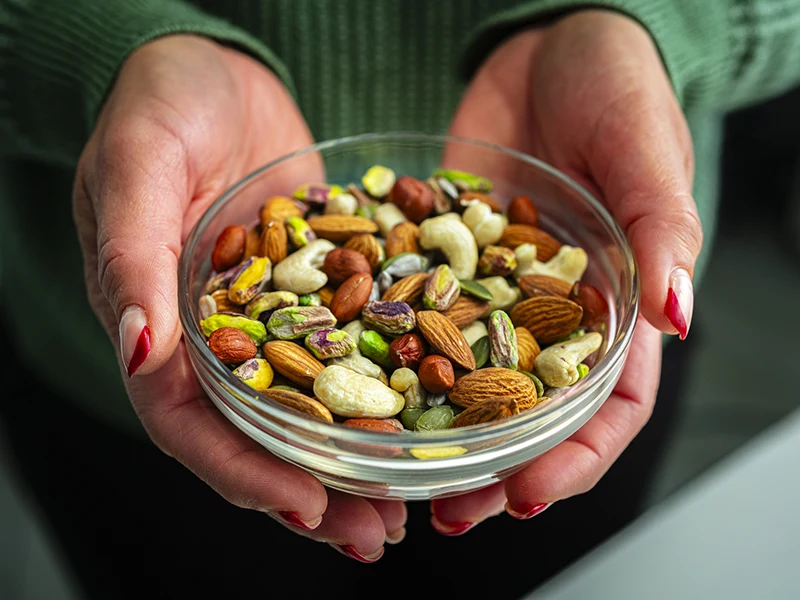 Closeup of hands holding a bowl of nuts