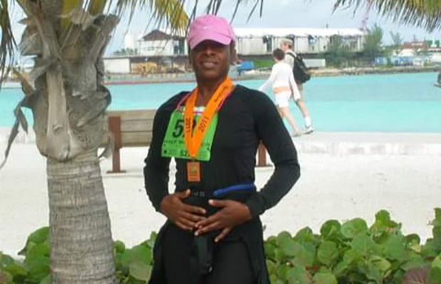 Women wearing a pink hat after a race, she had a medal around her neck, in the background you see a beach