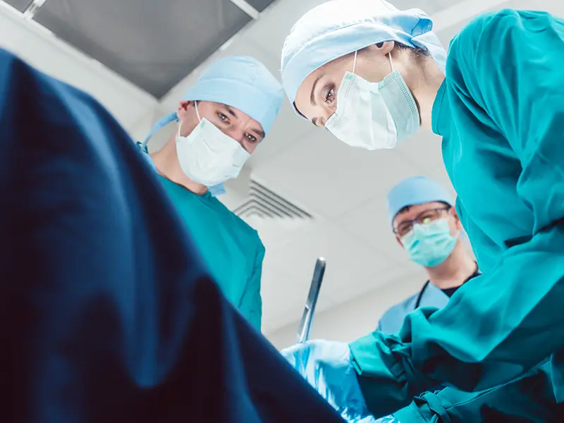 Three medical professionals performing surgery