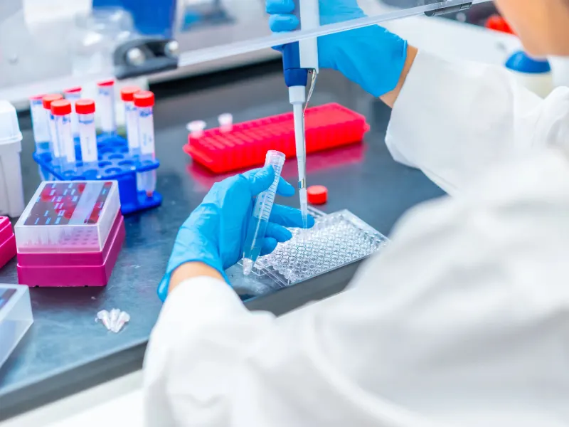 A close up of a medical professional working in a lab utilizing a tube device