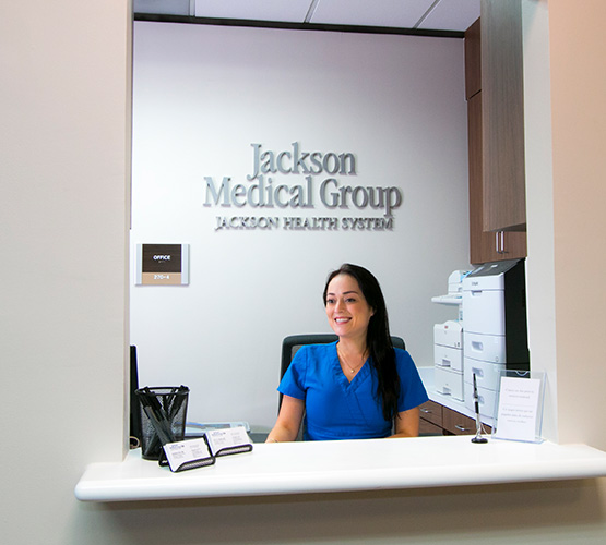 A receptionist sitting at her desk and smiling at a Jackson Medical Group location