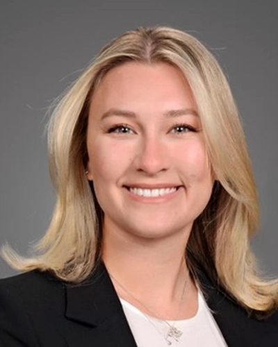 Professional headshot of Jackie-J, a woman smiling, against a gray studio background