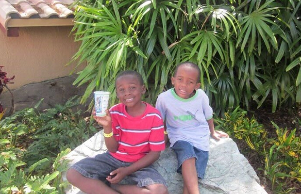 Two children sitting on a rock, smiling at the camera