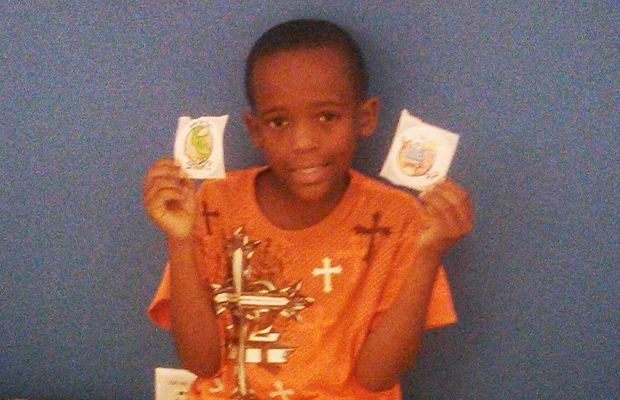 boy smiling at the camera while showing something he is holding