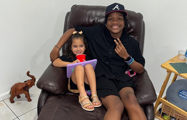 A young boy sitting on a sofa next to a little girl.