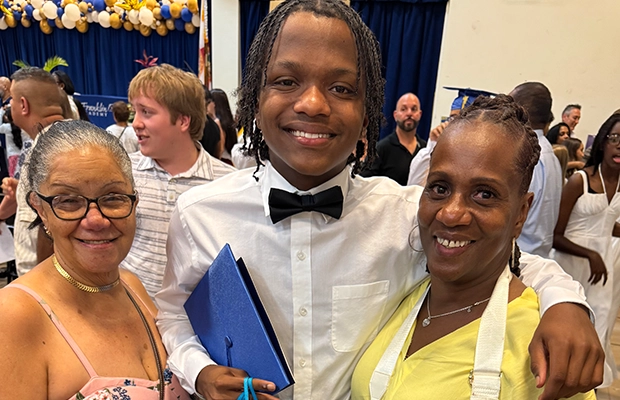 A young man posing with his mom and grandmother on his graduation day.