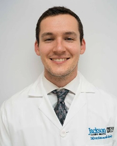 Professional headshot of Karl-Hall, a man smiling, against a white studio background