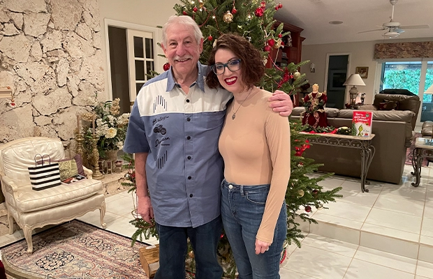 Adult man posing and smiling at the camera next to a young woman