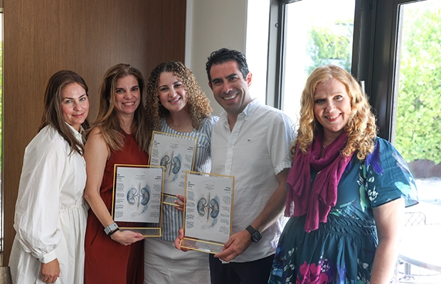 five people posing and smiling at the camera
