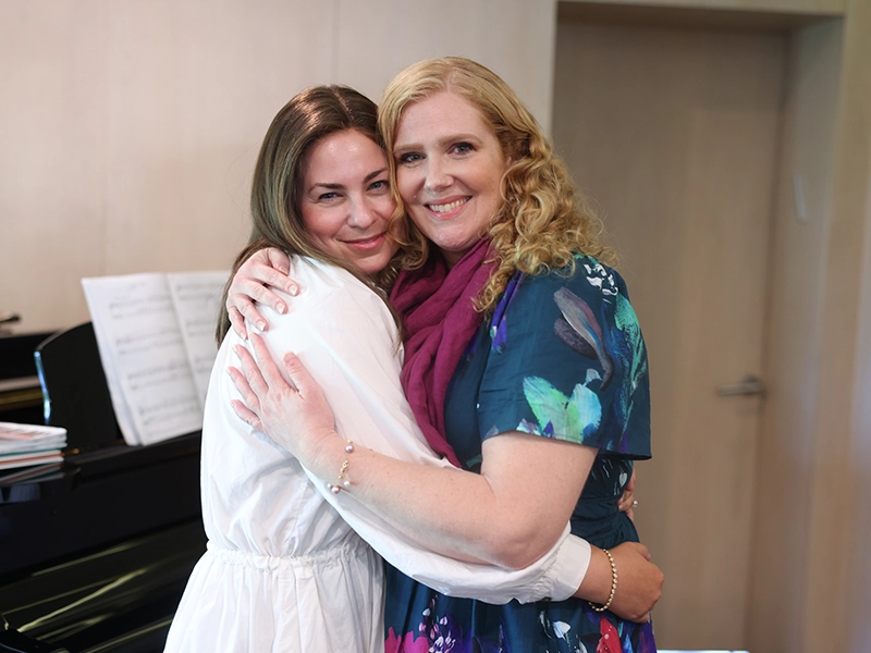two women embracing and smiling at the camera