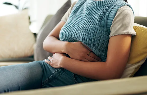 Close-up of a seated woman's hands holding her stomach