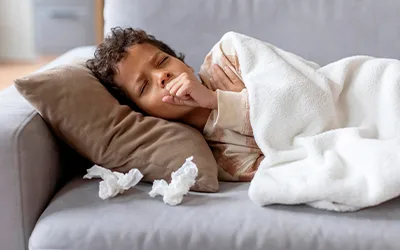 Boy lying in bed while coughing