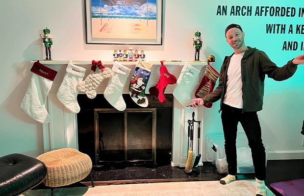 man posing next to a Christmas decorated fireplace
