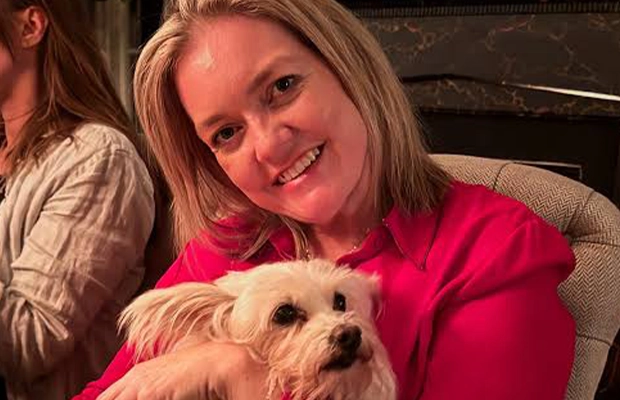 Blonde woman in red sweater holding a white dog