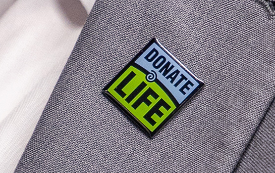 Closeup of a donate life button on a gray suit jacket