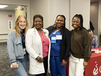Four medical professionals smiling at the camera, they're at an event space
