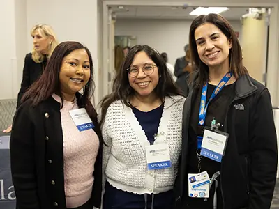 Three women at an event, they smile at the camera