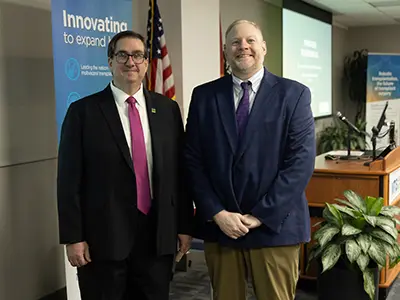 Two professionals standing next to each other, they smile at the camera