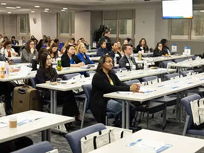 A group of people sitting at tables and watching a presentation