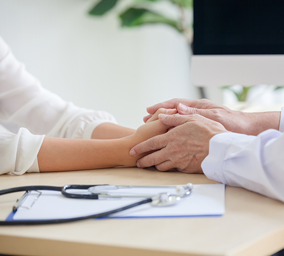 Close up of the hands of a doctor as they hold a patients hands to reassure her