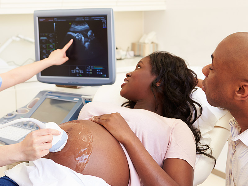 A pregnant women receiving an ultrasound as her husband and her look at the screen