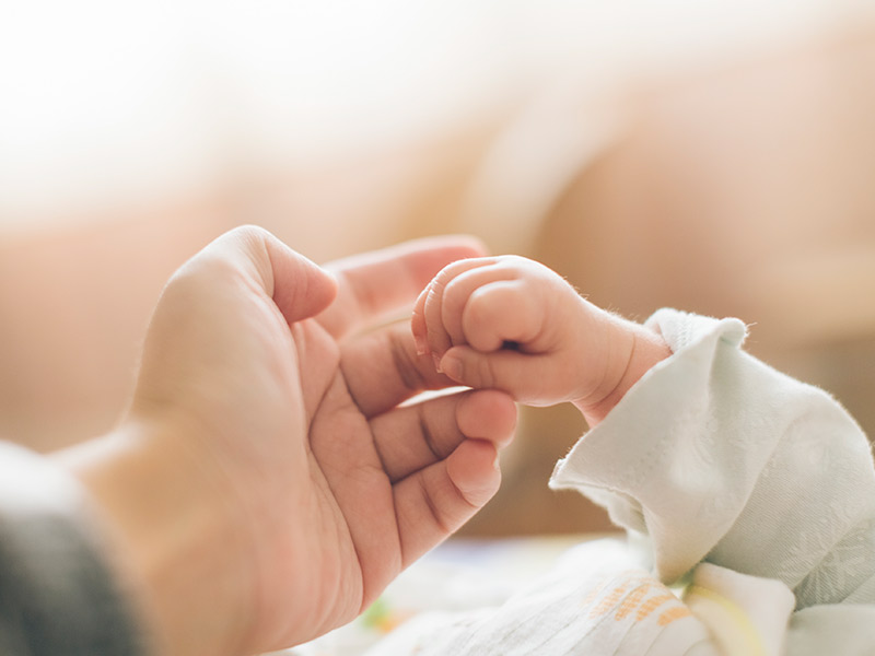 Close up of a babies hand holding a parents index finger