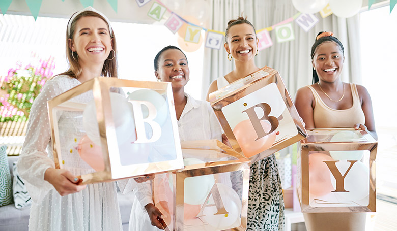 Four women smiling at the camera, each women holds a clear box that reads BABY