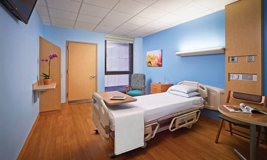 A maternity suite with a bed, table, chair, and flower