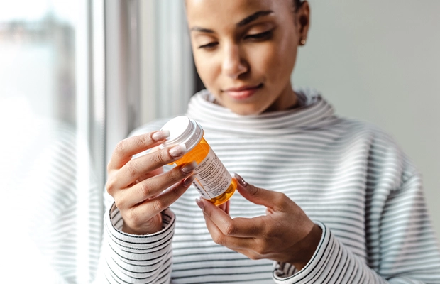 Close-up of a woman examining an orange medication bottle.