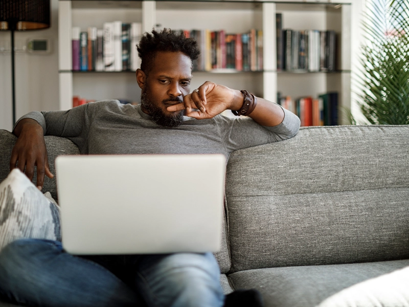 man sitting on a sofa while using his laptop