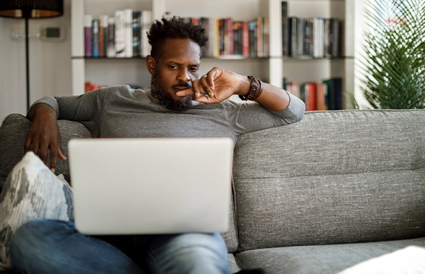 man sitting on a sofa while using his laptop