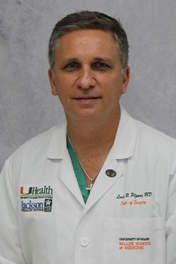 Headshot of a medical professional, he smiles at the camera, he has on white coat