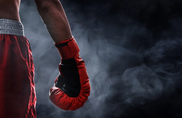 closeup of back and leg of man from behind wearing boxing gloves