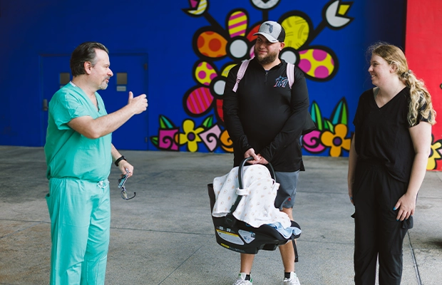 a couple of parents holding their baby while talking to a doctor