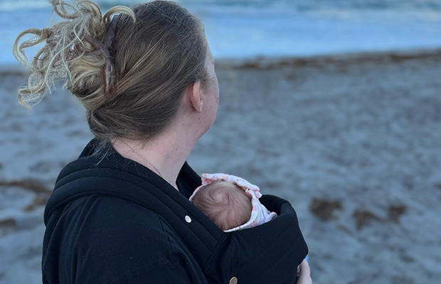 Woman carrying her baby by the sea