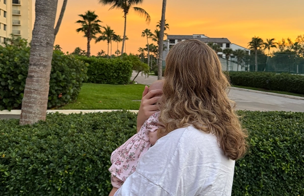 a woman carrying her baby at sunset